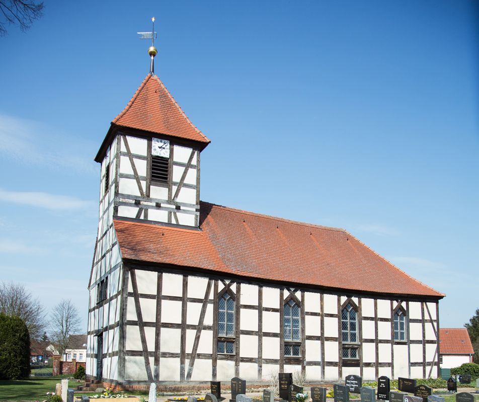 Eine Fachwerkkirche mit Kirchturm, umgeben von einem Friedhof.