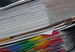 Ein Stapel Akten mit bunten Registern, die die Kirchenverwaltung darstellen.