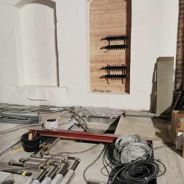 zwei Kircheninneres in Renovierung, mit offenem Boden und Weinregalen in der Wand.