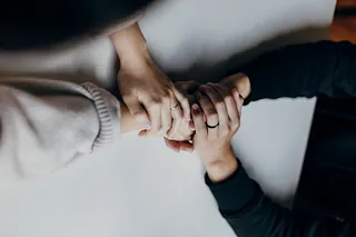 Drei Hände, die ineinandergreifen, als Symbol der kirchlichen Gemeinschaft.